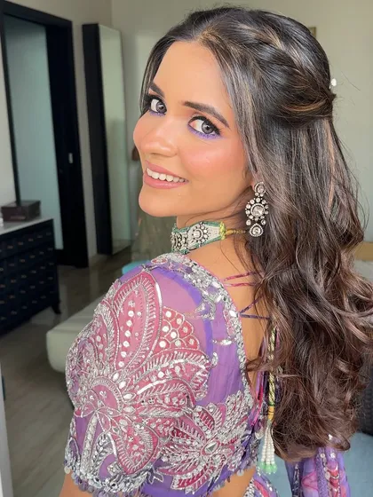 A half-up style with a simple braid and soft waves, a versatile look for a Mehendi or Haldi.