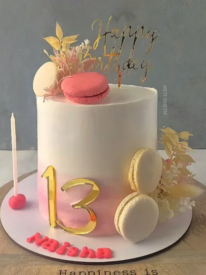 A milestone 13th birthday cake for Naisha. This elegant Vanilla Blueberry cake features a soft pink ombre, delicate macarons, and gold accents for a sophisticated, minimalist design.