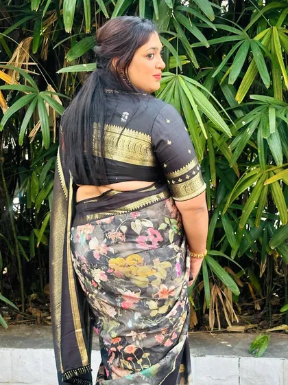 A client wearing a black floral organza saree with a matching black brocade blouse, a chic and modern ethnic look.