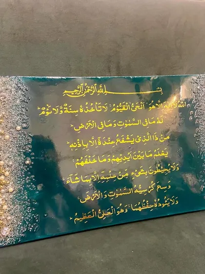 An elegant Ayat ul Kursi plaque in a rich emerald green and gold color scheme. The borders are adorned with a cascade of crystals and pearls, adding a touch of luxury to the sacred verse.