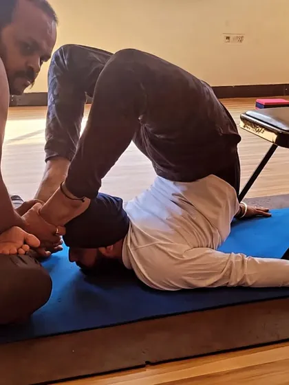 I am assisting a student in a deep spinal twist and backbend. My hands-on adjustment helps him to safely deepen the pose and release tension in the back.