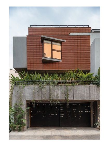 The street-facing elevation of the Nairy Residence is designed for privacy at the ground level, with a perforated metal gate and a solid concrete plinth. Above, a projecting bay window with an angled sill creates a dynamic architectural feature while capturing specific views.