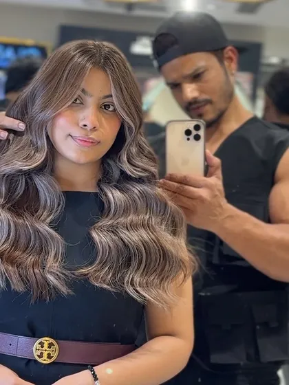 Taking a mirror selfie with a happy client to capture the final result of her icy blonde transformation. The color is vibrant, and the hair is styled into beautiful, flowing waves.