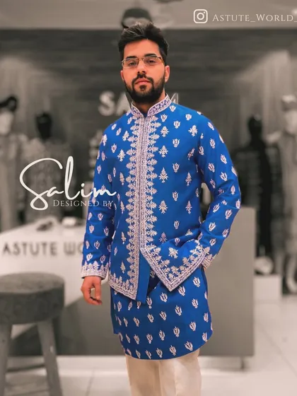 Color can make a powerful statement. This is a custom-designed Indo-Western set in a vibrant royal blue, featuring detailed white embroidery along the opening and cuffs for a sharp, celebratory look.