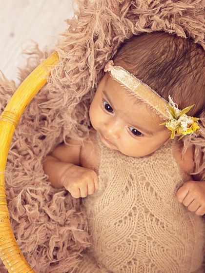 This portrait showcases an alert and curious newborn. The earthy tones of the knit outfit and the textured basket create a warm, organic setting for capturing those beautiful, wide-open eyes.