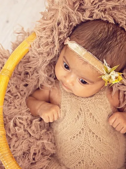 This portrait showcases an alert and curious newborn. The earthy tones of the knit outfit and the textured basket create a warm, organic setting for capturing those beautiful, wide-open eyes.