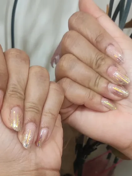 A full set of nails with a shattered glass effect using gold holographic foil over a natural, sheer base.