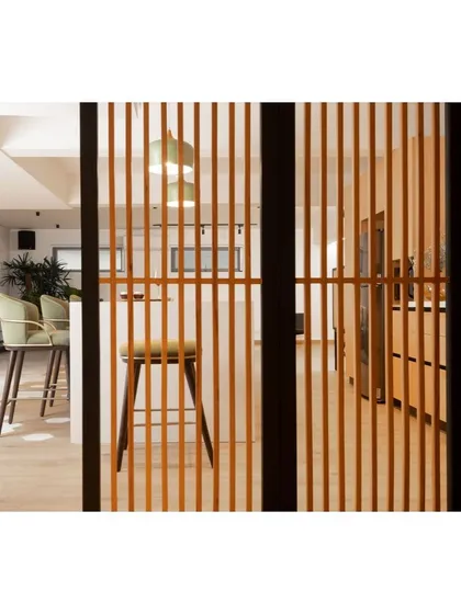 A wooden slat partition provides a visual separation between the kitchen and other areas without blocking light. This detail adds warmth and texture while maintaining the open and minimalist feel of the apartment.