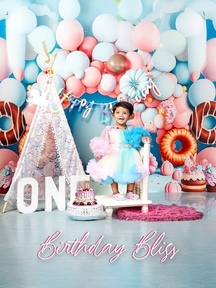 Birthday bliss in a flurry of pastel colors. This little girl, dressed in a rainbow tulle dress, is the picture of happiness as she celebrates turning one in our donut-themed wonderland.