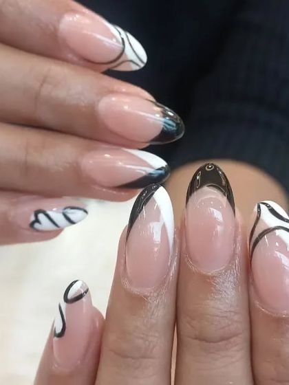 A modern and graphic take on the French manicure, with abstract black and white lines and shapes.