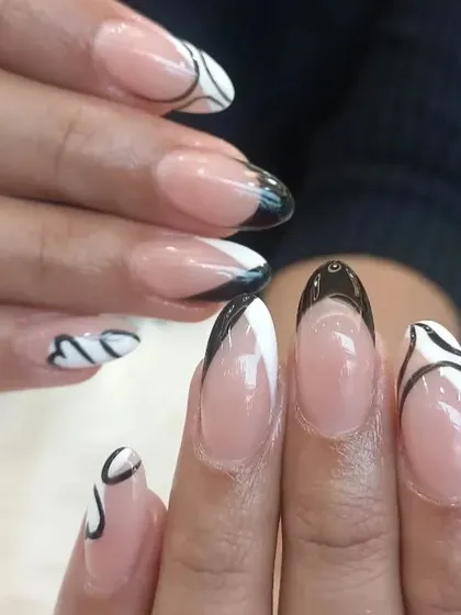 A close-up look at the intricate line work on this abstract French manicure. The combination of black and white swirls on a natural base creates a truly artistic and modern nail design.