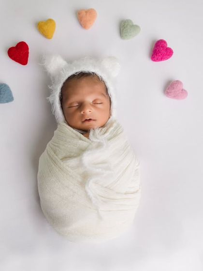 A minimalist and adorable setup with a simple white wrap and a rainbow of felt hearts. The bear bonnet adds a touch of whimsy.