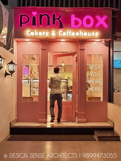 The entrance acts as a perfect frame for the sweet world inside. This view shows a customer stepping into the bakery, drawn in by the glowing pink facade.