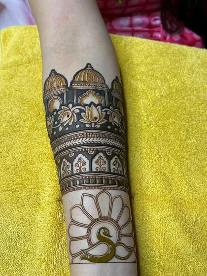 A work-in-progress shot of a beautiful arm band featuring palace architecture, lotus flowers, and a peacock outline ready to be filled.