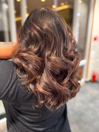 A side view of the mocha hair color balayage, showing the beautiful, flowing curls and rich tones.