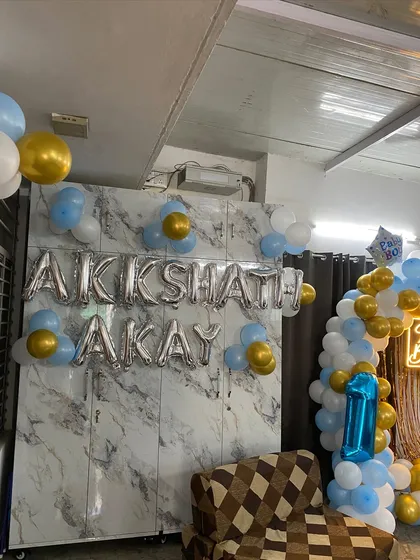 A personalized touch with foil balloons spelling out the name 'AKKSHAT AKAY' on a marble-patterned wall.