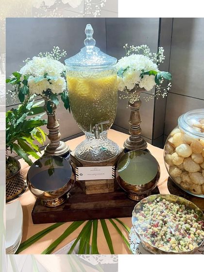 A clean and elegant golgappe station with a glass dispenser and shiny brass bowls, perfect for a more formal event.