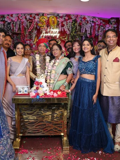 The entire family gathers around the couple for a group photo during their golden wedding anniversary celebration.