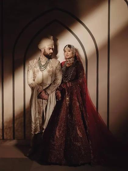 Amidst the grandeur, the soul of the event is in the human connection. This portrait from a Nikah ceremony captures the serene and profound bond between the couple, framed by the simple elegance of Mughal-inspired arches and soft, ethereal light.