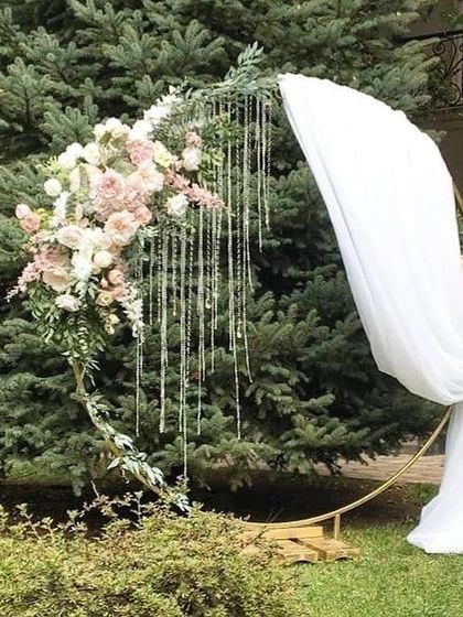 A close-up of a modern circular arch, beautifully decorated with a floral arrangement and hanging crystal strings.