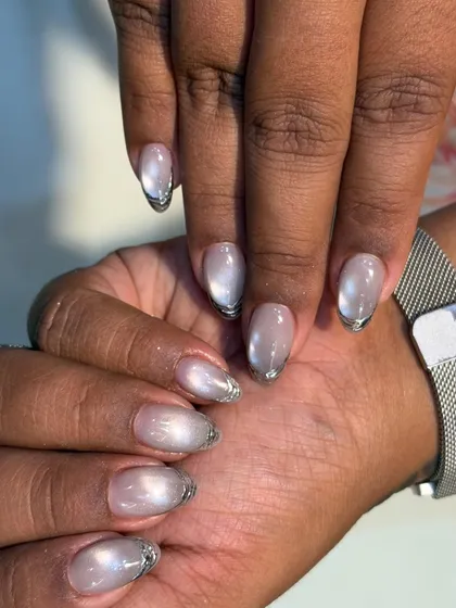 This is a beautiful example of a glass finish cat-eye effect on a shorter, almond-shaped nail. The silver chrome tip adds a modern French manicure twist.