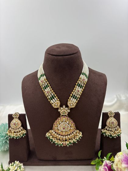 Our "Indira" premium antique gold necklace set. This long necklace features a large, intricately designed pendant with Meenakari work and comes with matching statement earrings.