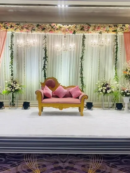 A soft and romantic stage design with blush pink drapes and hanging floral strings. This setup creates a warm and inviting atmosphere for any celebration.