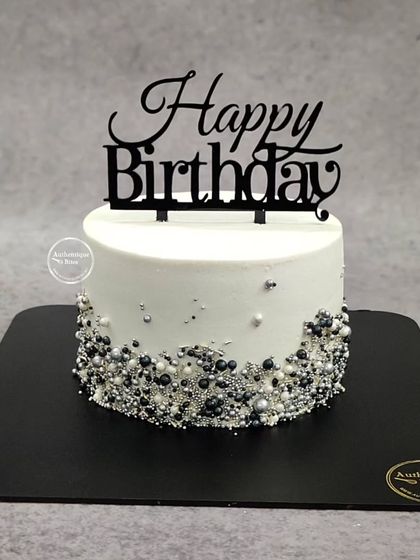 A classy black and silver confetti cake. The sprinkles at the base give it a fun, celebratory feel.