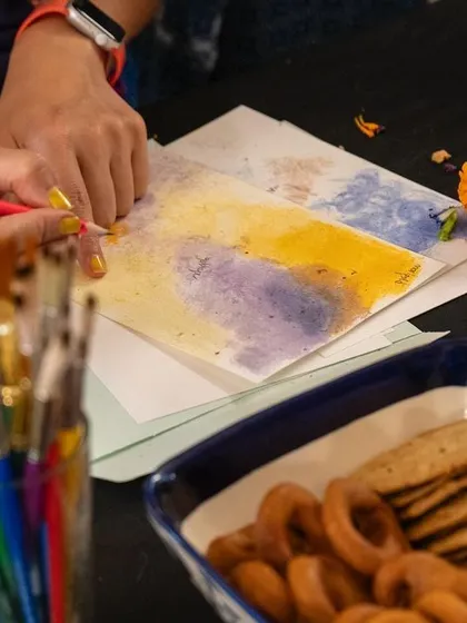 A participant adds final touches to their artwork, with a bowl of snacks nearby. Our workshops are relaxed and friendly, with plenty of time for creativity, conversation, and of course, chai and snacks.