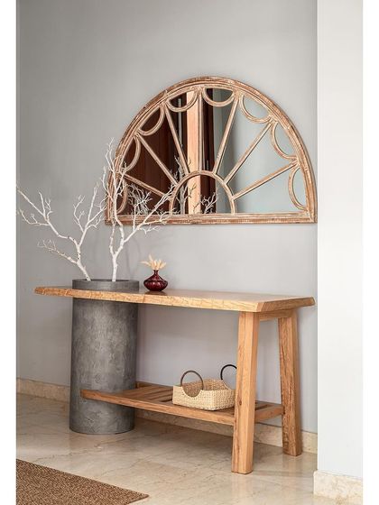 The focal point of this foyer is the custom console, which combines a raw concrete cylinder with a live-edge wood top. Above it, a distressed arched mirror adds to the rustic, vintage charm.