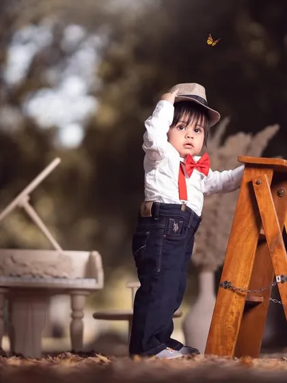 A stylish little boy ready for his performance. Tipping his hat, he looks every bit the part of a charismatic musician in this outdoor shoot.