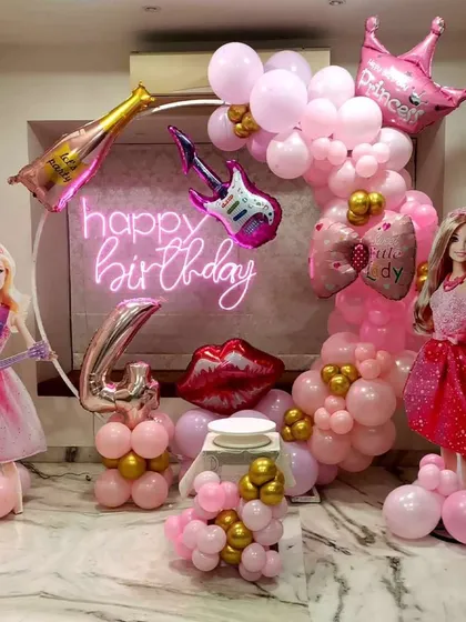 A glamorous Barbie-themed birthday party perfect for a little rockstar, featuring pink and gold balloon decor, Barbie doll cutouts, and a "Happy Birthday" neon sign.