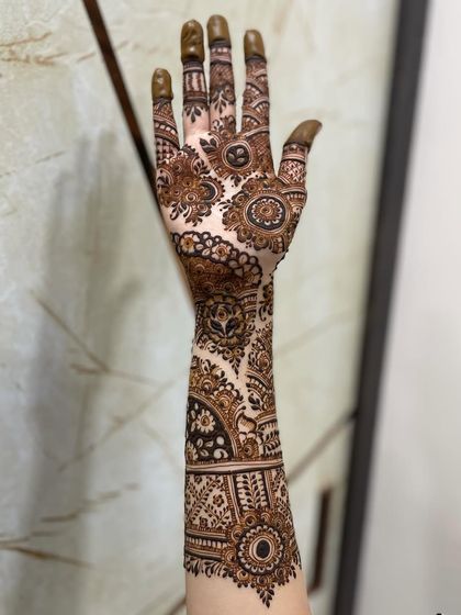 A single-arm view showcasing a full bridal design. You can see the flow from the detailed palm work to the architectural bands on the forearm, ending in a delicate border.