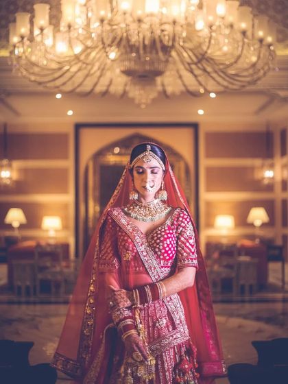A bride stands under a massive chandelier in a hotel lobby, a shot that emphasizes grandeur and elegance.