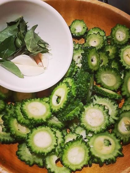 Getting ready to make a quick and easy side dish of crispy Karela fry. Here are the freshly sliced bitter gourd rounds with garlic and curry leaves.