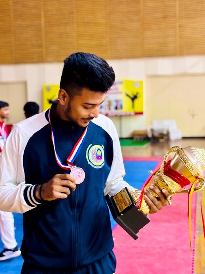 Victory at the All India University Games. An athlete holding his trophy and medal, a proud moment for the academy.