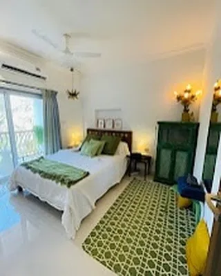 This is the heart of the apartment's calm, the Green Room. I designed this master bedroom to be an earthy, serene space with its own private balcony access, perfect for unwinding. The warm lighting and comfortable furnishings make this a truly restful sanctuary in our Siolim holiday rental.