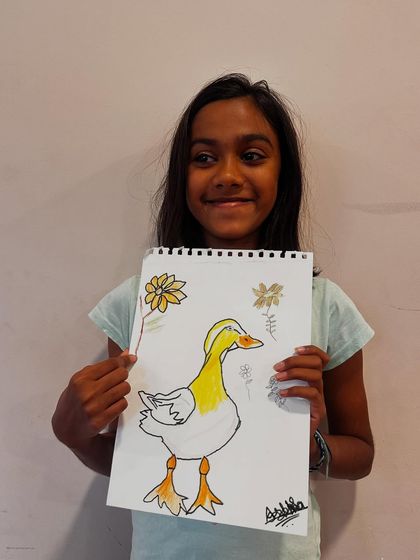 This student is all smiles as she presents her beautifully outlined and colored duck drawing.