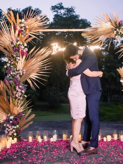 An emotional embrace after the proposal, framed by the stunning floral arch against the evening sky.