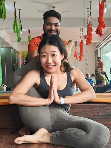This is a "Jai Ho!" moment. With careful guidance and support, this student achieves the advanced Eka Pada Sirsasana (One-Leg-Behind-Head Pose). Her smile says everything about the joy and confidence that comes from progressing in your practice.