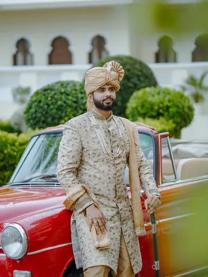A stately pose against a vintage car and lush palace gardens. This image captures the groom in his element, embodying the grace and power of a king in his kingdom.