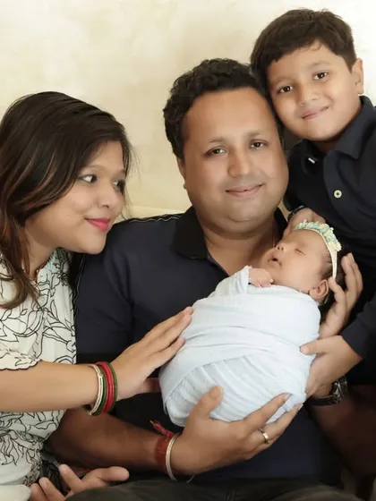 A lovely family photo from a lifestyle session. The mother gazes lovingly at her husband as he holds their newborn, while their older son smiles proudly for the camera.