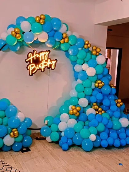 A wave-like balloon arch on a circular frame. This unique design uses shades of blue and white with small gold accents for a dynamic and modern look.