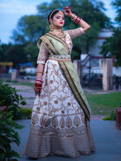 An elegant white lehenga with gold paisley embroidery and a contrasting light green dupatta. This is a sophisticated and graceful option for a daytime wedding or reception.