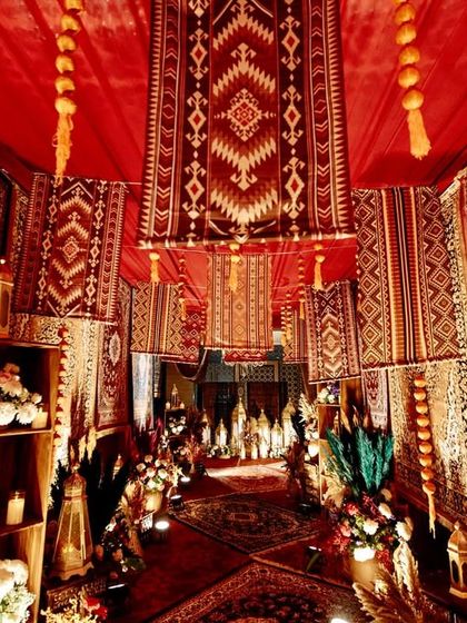 An immersive entrance designed to feel like a vintage Persian bazaar, with walls and ceilings completely covered in rich, patterned rugs and warm lighting from traditional lanterns.