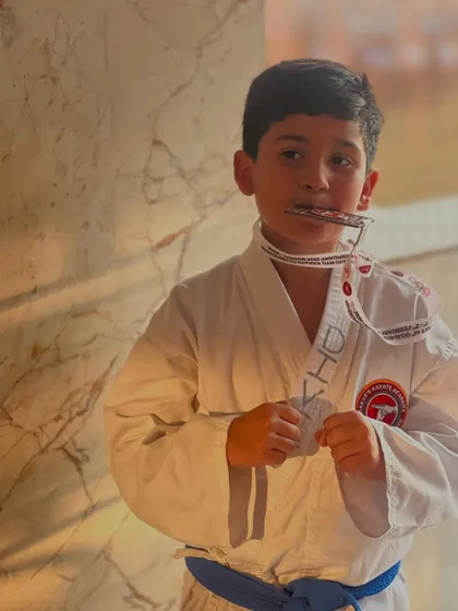 A quiet moment of pride for a young champion. The journey of a karateka is filled with challenges and rewards, and we celebrate them all.
