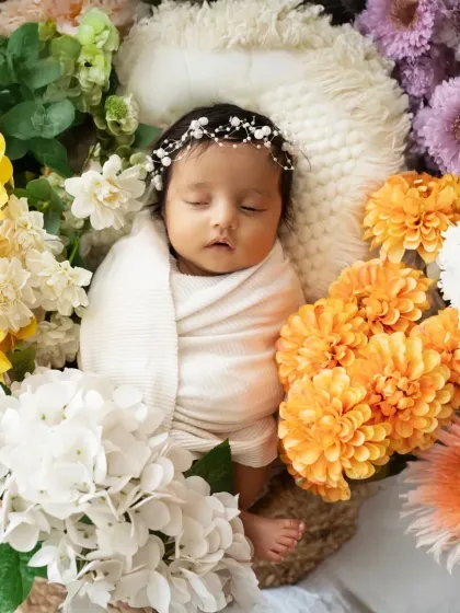 An overhead shot of a newborn surrounded by a vibrant ring of yellow, orange, and white flowers. Floral arrangements add a beautiful touch of color and nature to our photos.