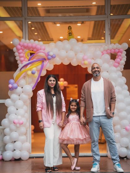 A lovely family photo at the entrance of the unicorn party, under a beautiful white balloon arch.