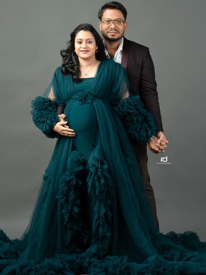 A classic pose for an expecting couple. Holding hands and looking at the camera, this shot in a stunning green gown is a beautiful way to formally document your pregnancy.
