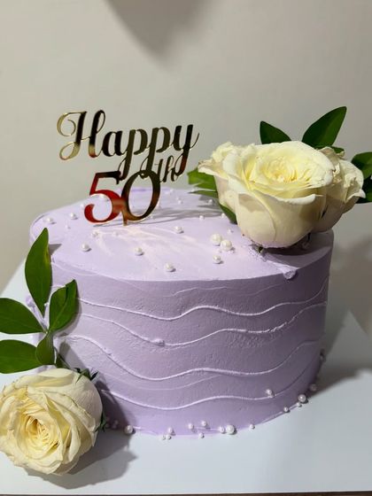 A lovely lavender cake for a 50th birthday. This one-kg Dutch Truffle cake is decorated with fresh white roses and a golden "Happy 50th" topper.